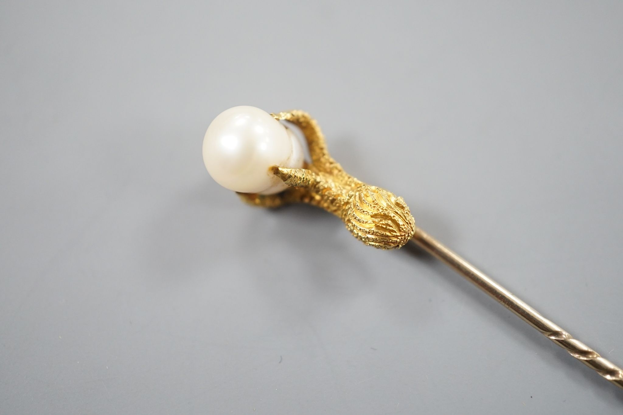 A 19th century yellow metal stick pin, the terminal modelled as an eagle's claw grasping a baroque pearl, 78mm, gross weight 3.3 grams, with box.
